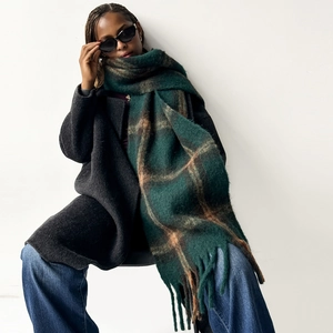 Detailed view of thick forest green and caramel brown plaid wool scarf with long tassels