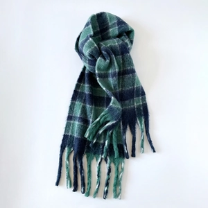 Détails d'une écharpe en laine à carreaux bleu foncé et vert avec de longues franges