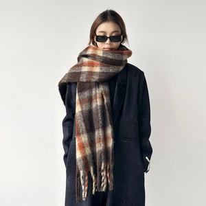 Detail of a thick plaid wool scarf with tassels and brown check pattern for winter