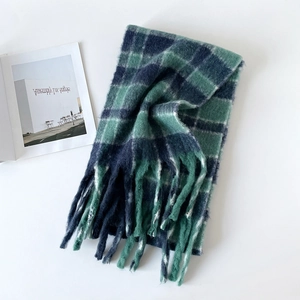 Détail d'une écharpe épaisse à carreaux bleus et verts avec de longues franges tressées