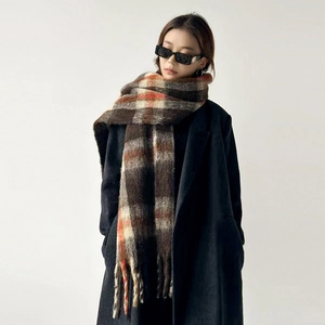 Close-up of thick plaid wool scarf with fringe detail in brown and red patterns