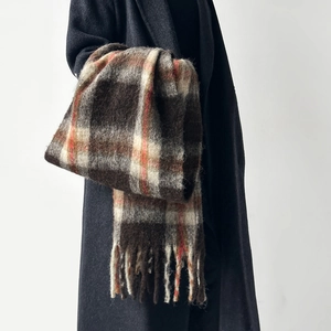 Detail of a thick wool scarf with classic plaid pattern and long tassels for winter