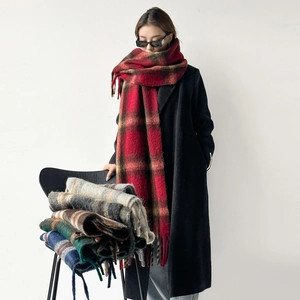 Detail shot of thick knit wool scarf featuring large plaid patterns and long fringe tassels