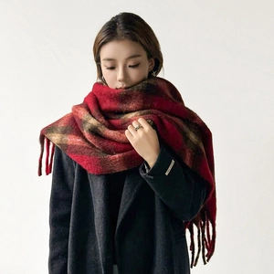 Detail of red and brown plaid wool scarf with fringe on a gray coat for winter warmth