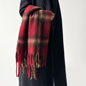 Close-up detail of warm red brown plaid wool scarf with classic fringe and soft texture