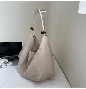 Detail of minimalist beige canvas tote bag featuring unique brown wooden bead strap accents