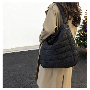 Detail of black quilted shoulder bag with soft textured fabric and square pattern