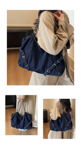 Detail of blue denim tote bag with silver metal buckles and chain shoulder strap
