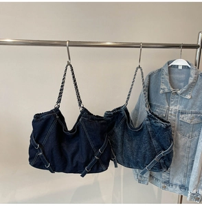 Detail of blue denim tote bags with contrast stitching and metal chain straps