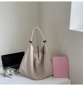 Detail of beige hobo shoulder bag with thick rope strap and wooden bead accents