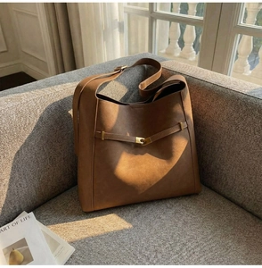 Detailed macro view of caramel brown suede tote bag with elegant golden metal buckle
