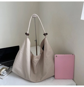 Detail view of large beige hobo bag with wood bead accents and textured fabric material