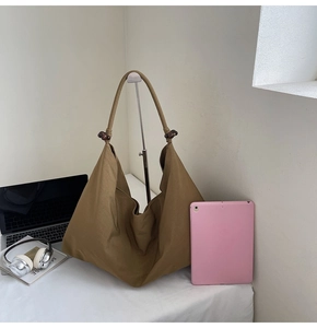 Detail view of large khaki tote bag with wooden bead accent and spacious interior for laptop