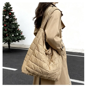 Detail of khaki quilted tote bag with pleated texture shown in an outdoor street scene