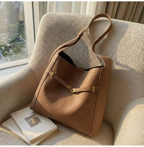 Close-up of vintage brown bucket bag with gold hardware buckle on a cozy chair