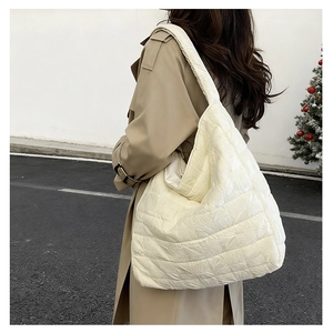 Detail view of large quilted tote bag with pleated texture on casual street model