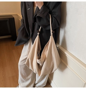 Detail view of large apricot fabric tote bag with bead strap accents on model's shoulder