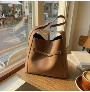 Detailed macro view of caramel brown leather bucket bag with elegant golden metal buckle