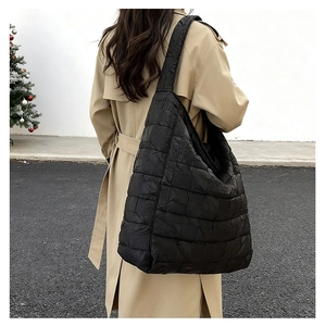 Detailed view of black quilted tote bag with pleated texture during outdoor use