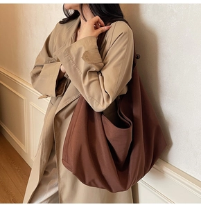 Detail of a large dark brown slouchy tote bag worn with a stylish khaki trench coat