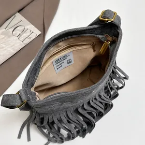 Detalle interior del bolso de ante con forro marrón y bolsillo con cremallera dorada