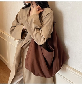 Detail view of a large brown slouchy canvas shoulder bag showing soft texture and drapes