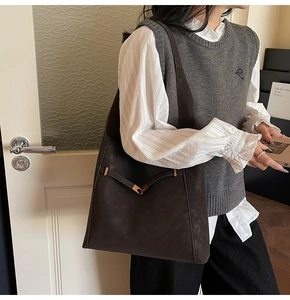 Detail view of large dark coffee bucket bag with golden V-shaped hardware and vintage suede texture