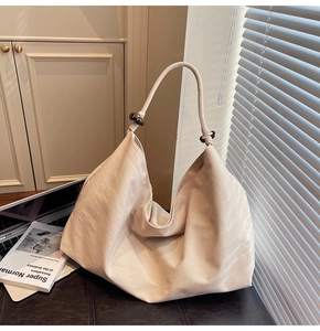Detail of cream shoulder bag with soft texture and distinctive dark wooden bead accent
