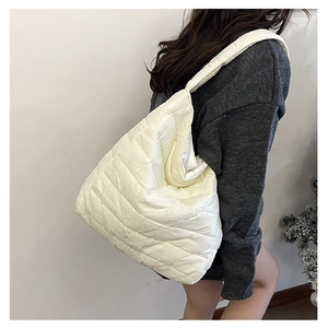 Detail of white quilted tote bag featuring a padded texture and soft shoulder strap