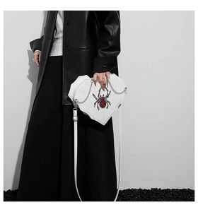 Detail der weißen herzförmigen Tasche mit Spinnennetz-Nähten und roter Strass-Spinne