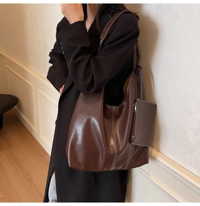 Détail d'un grand sac cabas en cuir marron avec surpiqûres blanches et une petite pochette