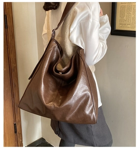 Side view of a vintage brown leather tote bag worn by a model in a retro setting
