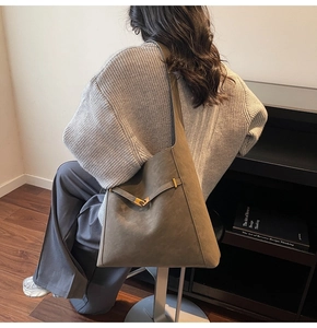 Detail of taupe suede shoulder bag with metal buckle shown in a lifestyle indoor setting