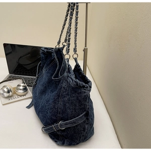 Detail of vintage washed denim shoulder bag with silver chain strap and drawstring design