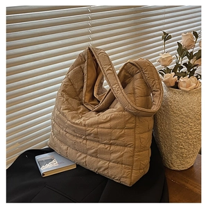 Detailed shot of oversized quilted tote bag with pleated texture on a wooden table