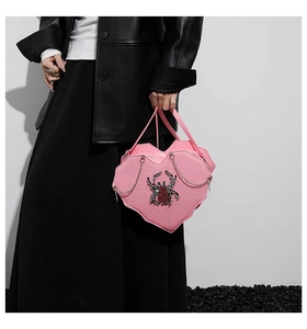 Detail einer rosa herzförmigen Handtasche mit Spinnennetzmuster und großem Strass-Spinne