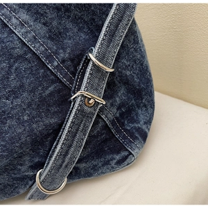 Macro shot of washed denim bag strap featuring silver metal buckles and neat stitching