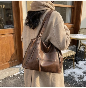 Detail of dark brown retro bowling bag with metal zippers shown in a winter street setting
