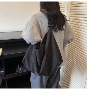 Detail of minimalist black oversized shoulder bag with knot decoration and wooden bead accent