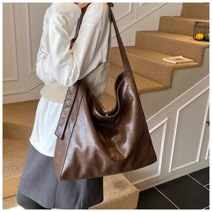 Detail view of large dark brown retro tote bag with wide shoulder strap and metal eyelets