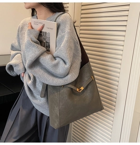 Detail of sage green large tote bag featuring gold buckle closure and textured leather