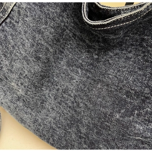 Detailed macro view of washed dark blue denim fabric with white contrast stitching