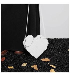 Detail der weißen herzförmigen Tasche mit schwarzem Spinnennetz und silberner Kette