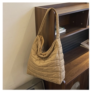 Detailed view of beige quilted tote bag hanging on a wooden shelf in a natural setting