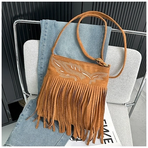 Détail du sac bandoulière en daim marron avec de longues franges et broderies blanches
