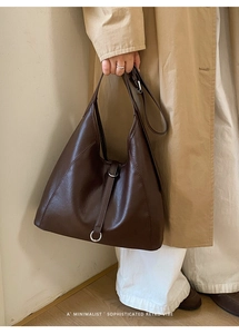 Détail du sac rétro en cuir marron foncé avec boucle à anneau argenté sur le côté