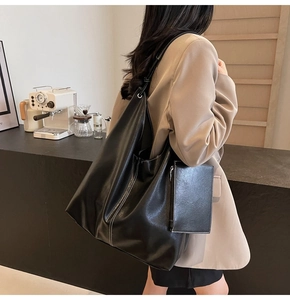Détail d'un sac cabas noir à coutures blanches avec pochette porté par un mannequin