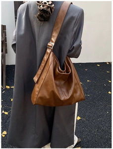 Close-up of brown vintage leather hobo bag with wide adjustable shoulder strap and silver buckle