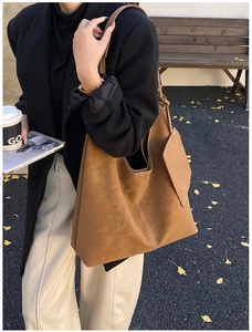 Close-up of brown suede tote bag with contrast stitching and matching pouch pendant