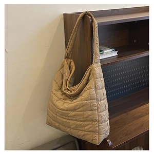 Detail of khaki quilted tote bag with square pattern hanging on a wooden shelf